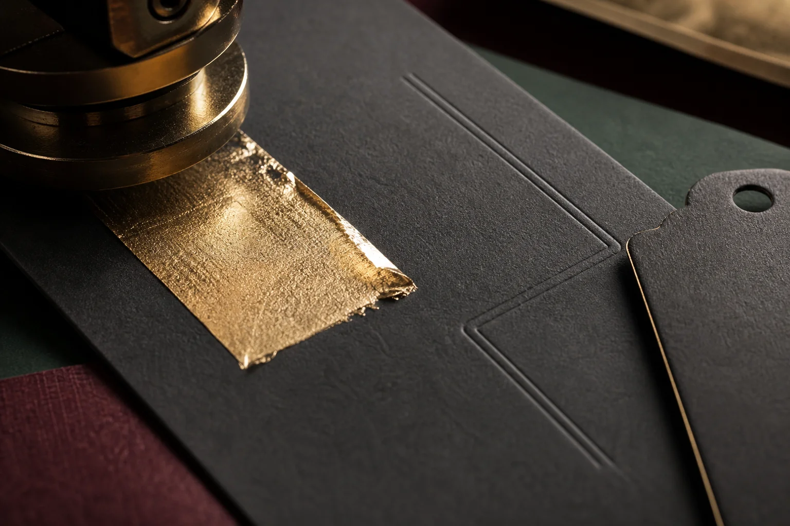 Champagne foil and blind debossing on a dark uncoated card beside a die-cut tag